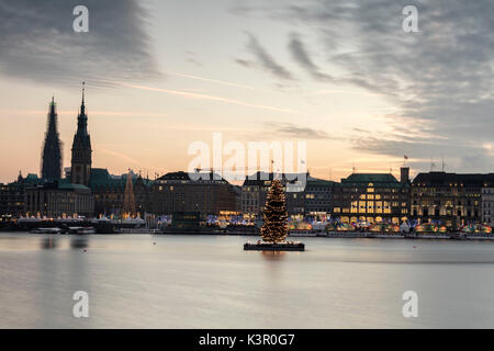 Die Farben und das Licht der Dämmerung auf der Binnenalster mit dem Weihnachtsbaum in seinem Wasser Hamburg Deutschland Europa ausgesetzt Stockfoto