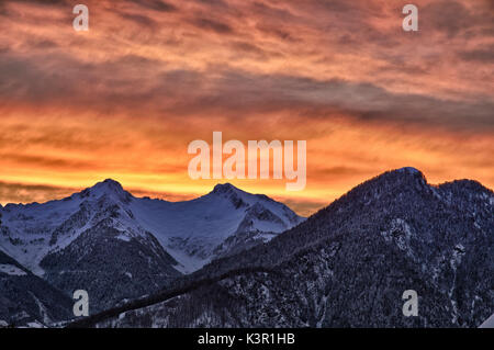 Ein Sonnenuntergang im Winter wärmt die Atmosphäre in Bitto Valley von albaredo nach einem starken Schneefall. Rasura. Valgerola. Bergamasker Alpen. Valtellina. In der Lombardei. Italien. Europa Stockfoto