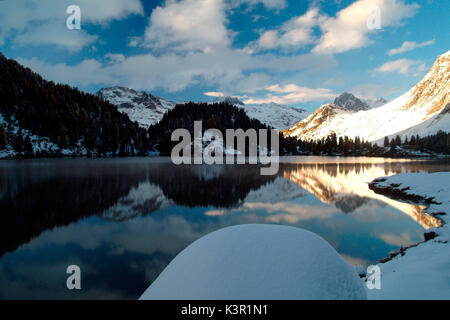 Die Peaks durch die neu auferstandene Sonne beleuchtet werden in See Cavloc am Malojapass wider. Engadin. Die Schweiz. Europa Stockfoto