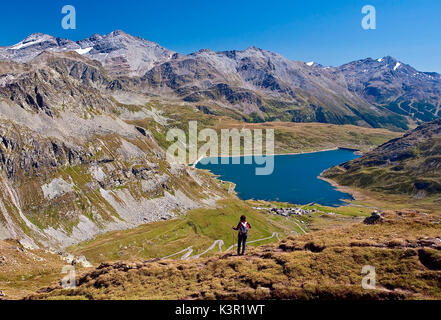 Wanderer beobachten die Landschaft mit Blick auf den Stausee von Montespluga und auf den Gipfeln Valchiavenna. Vallespluga. In der Lombardei. Italien. Europa. Stockfoto