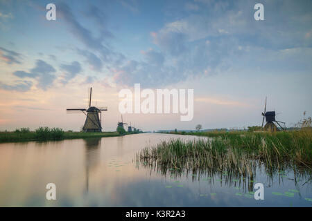 Blauer Himmel und rosa Wolken auf die Windmühlen in den Kanal in der Morgendämmerung Kinderdijk Rotterdam Südholland Niederlande Europa wider Stockfoto