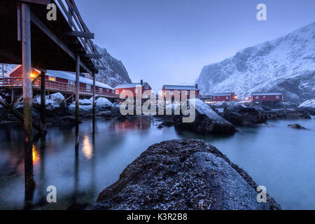 Typische Fischerhäuser genannt Fischerorten in die verschneite Landschaft in der Abenddämmerung Nusfjord Nordland County Lofoten Inseln Norwegen Europa Stockfoto