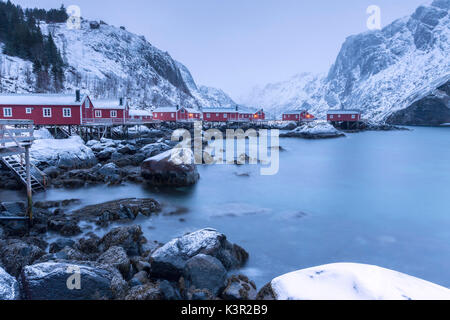 Typische Fischerhäuser genannt Fischerorten in die verschneite Landschaft in der Abenddämmerung Nusfjord Nordland County Lofoten Inseln Norwegen Europa Stockfoto