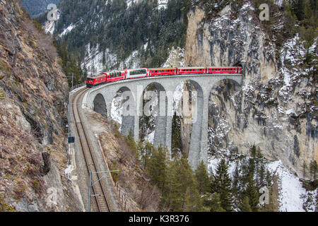 Bernina Express führt durch Landwasser Viadukt und verschneiten Wälder Filisur Kanton Graubünden-Schweiz-Europa Stockfoto