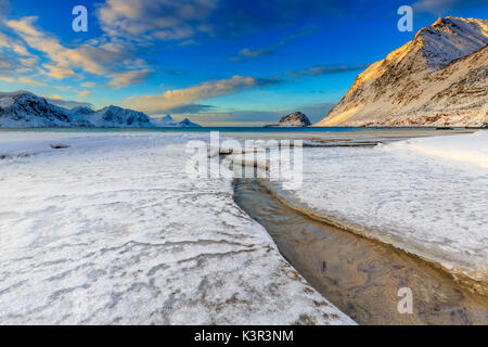 Die golden sunrise in einem klaren Bach auf das Meer, wo der Schnee geschmolzen ist. Haukland Lofoten norwegen Europa Stockfoto