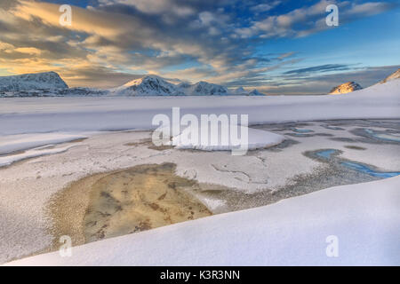 Die golden sunrise in einem Pool auf das klare Meer, wo der Schnee fast geschmolzen ist. Haukland Lofoten norwegen Europa Stockfoto