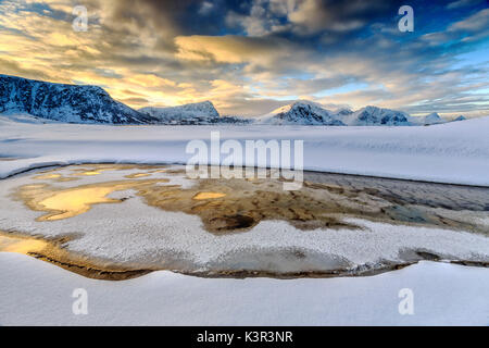 Die golden sunrise in einem Pool auf das klare Meer, wo der Schnee fast geschmolzen ist. Haukland Lofoten norwegen Europa Stockfoto