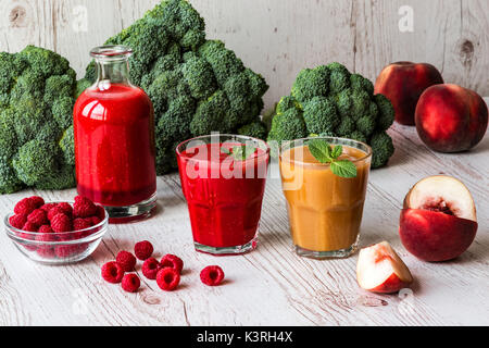 Gesunde Getränke. himbeere frischen Smoothie in Glas und Flasche und Pfirsich Saft auf weißem Holz- Hintergrund. Stockfoto