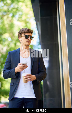 Portrait von gutaussehenden jungen Mann mit Smartphone Wandern in den Straßen der Stadt Stockfoto