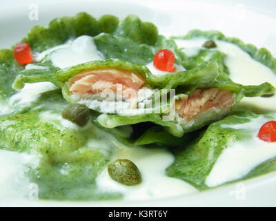 Lachs gefüllte Ravioli aus Spinat in Grün mit weißer Soße gekocht gemacht Stockfoto