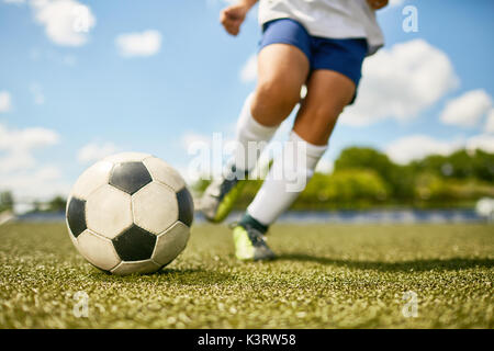 Niedrige Abschnitt Portrait von unkenntlich Teenager treten Kugel während der Fußball-Praxis im Feld Stockfoto