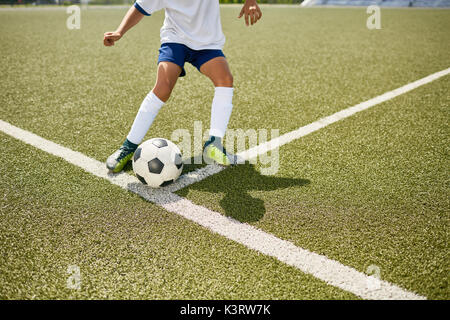 Niedrige Abschnitt Portrait von unkenntlich Teenager treten Kugel während der Fußball-Praxis im Freien Stockfoto