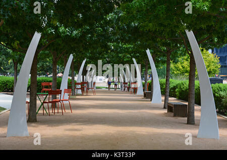 Die Eiche von Bäumen gesäumten Pfad am Klyde Warren Park in Dallas bietet Sitzgelegenheiten und dekorative Torbögen. Stockfoto