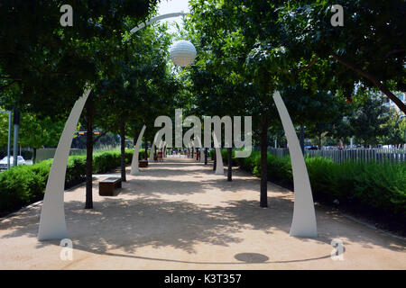 Die Eiche von Bäumen gesäumten Pfad am Klyde Warren Park in Dallas bietet Sitzgelegenheiten und dekorative Torbögen. Stockfoto