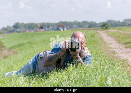 Männliche Festlegung auf ein Gras bank die Bilder mit einer Canon Kamera. Stockfoto
