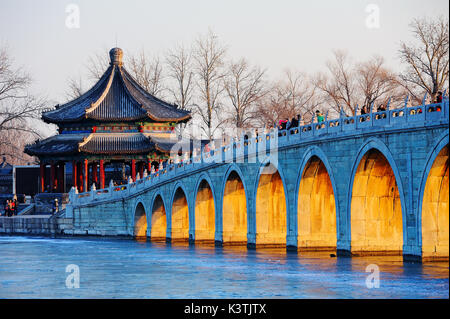 Der Sommerpalast im Winter, Kunming See wurde eingefroren, die Abendsonne durch die Brücke öffnen Der 17 Bogenbrücke. Stockfoto