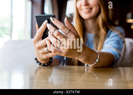 In der Nähe von Frauen Hände halten Zelle Telefon mit leeren Kopie Raum Geröll für Ihre Werbung Sms oder werbliche Inhalte, hipster girl Videos auf Handy während der Kaffeepause. Getönt. Selektive konzentrieren. Stockfoto