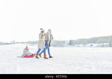 Familie spielen Schlitten auf dem Schnee im Winter Stockfoto