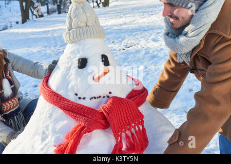 Man baut Schneemann im Garten mit seiner Familie und hat Spaß Stockfoto