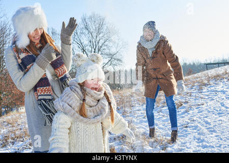 Eltern und Tochter als Familie viel Spaß mit Schneeballschlacht im Winter Stockfoto