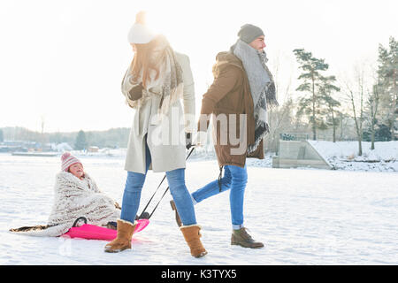 Vater zieht Kind mit Schlitten auf dem Schnee Whilte bei einem Spaziergang im Winter Stockfoto