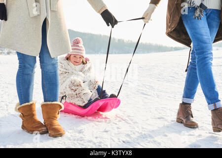 Familie wandern mit Kind auf Schlitten im Winter Stockfoto