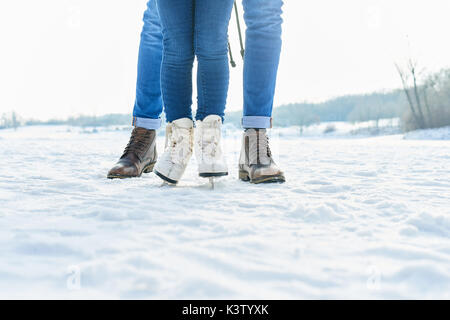 Kind Schlittschuhen mit Vater im Winter und der Praxis auf dem Schnee Stockfoto