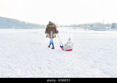 Vater und Kind Rodeln im Schnee im Winter Stockfoto