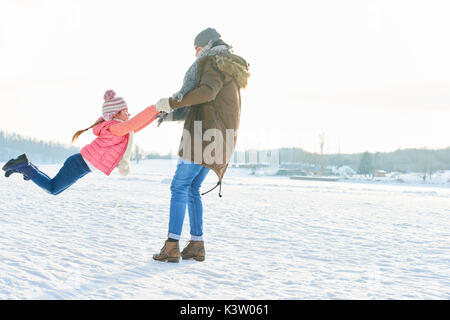 Kind und Vater spielen vorgibt, im Winter im Schnee zu fliegen Stockfoto