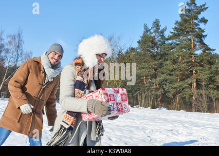 Junges Paar bringt Weihnachten Geschenk als Überraschung im Winter Stockfoto