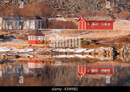 Einige rorbuer spiegelt sich auf dem Wasser des in der Nähe von Fjord in die Lofoten, Norwegen. Stockfoto