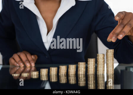 Nahaufnahme einer Geschäftsfrau, die Stapel von Münzen Stockfoto