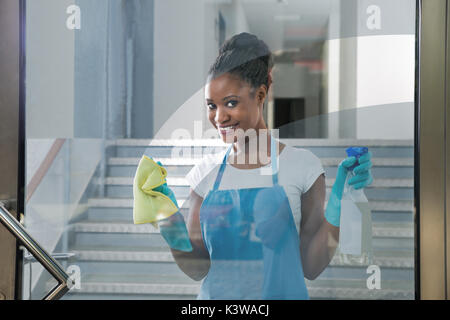 Portrait von lächelnden afrikanische Frau reinigen Glas mit Rag Stockfoto