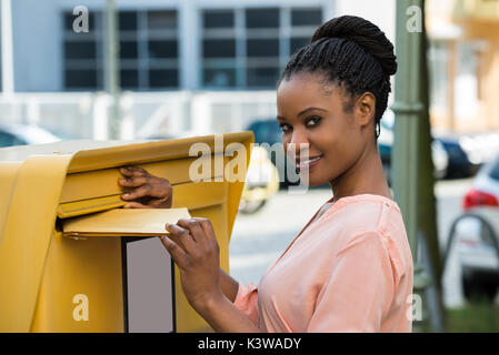 Junge afrikanische Frau einfügen Schreiben in der Mailbox Stockfoto