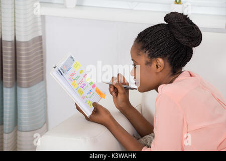 Lächelnden jungen afrikanischen Frau Prüfungsschema im Tagebuch Stockfoto
