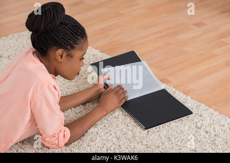 Junge afrikanische Frau auf der Suche leer Fotoalbum im Wohnzimmer Stockfoto