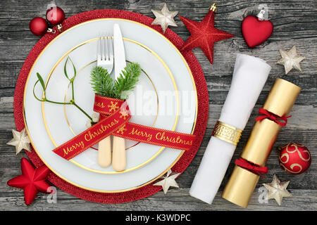 Weihnachten Tisch mit Tellern, Besteck mit Tanne und Farbband, Serviette, Cracker und Christbaumkugel Dekorationen auf Holz Hintergrund. Stockfoto