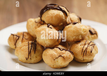 Profiteroles mit feiner dunkler Schokolade auf Platte Stockfoto