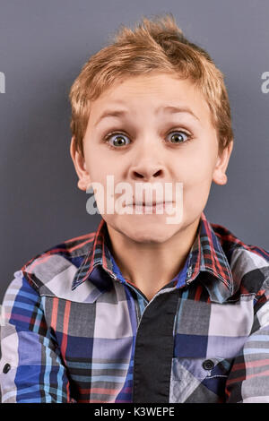 Portrait von überrascht kleiner Junge. Schöne blonde Haare school Junge mit weit geöffneten Augen geschockt. Studio shot von überrascht kleiner Junge hautnah. Stockfoto