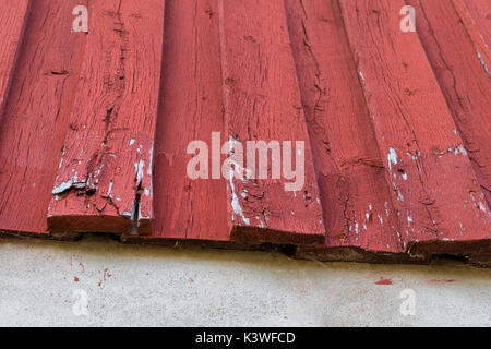 Ein Rot lackiertes Holz Fassade an einem Haus, das in der unteren ersetzt Reparatur verdorben ist. auseinander Stockfoto