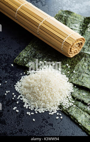 Grüne nori Blatt, Reis und Bambus Matte auf Schwarzen Tisch. Stockfoto