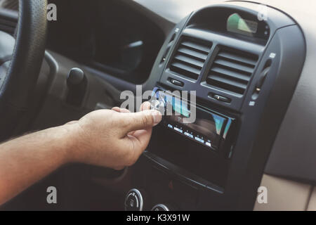 Die Hand des Mannes dreht die Lautstärke in einem retro toning Auto. Stockfoto