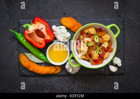 Schüssel mit gedünstetem Gemüse Ragout und Rohstoffe. Gesunde, vegetarische Kost Konzept. Stockfoto