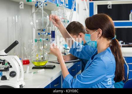 Junge Wissenschaftler in Uniform, einige Untersuchungen in einem Labor. Gesundheitswesen und Biotechnologie Konzept Stockfoto