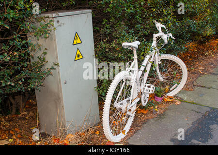 Das moderne Phänomen einer Gedenkstätte Ghost Fahrrad angekettet an einen Pfosten an der Szene von einem tragischen tödlichen Unfall mit einem Kraftfahrzeug und einem Radfahrer auf Th Stockfoto