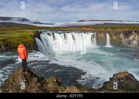 Mann, der vor Wasserfall Godafoss, Island Stockfoto