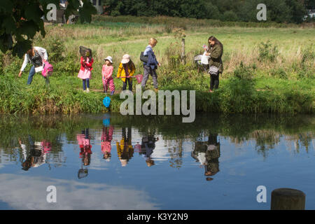 Familie mit drei Kindern in bunten Kleidern mit Netzen im Fluss in der Nähe von Godalming, Surrey, Großbritannien Stockfoto