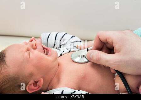 Dem kleinen neugeborenen Baby weinen Während geprüft durch Arzt Stockfoto