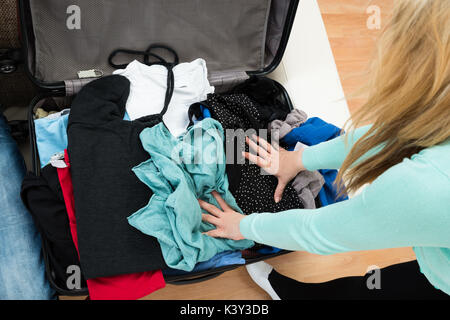 Hohe Betrachtungswinkel von Frau Verpackung Kleidung im Koffer Stockfoto