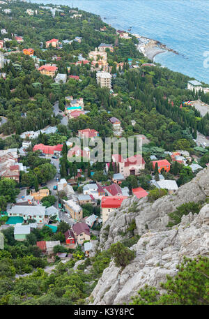 Küstenstadt mit einer Vielzahl der Häuser unter den Bäumen am Strand. Die Aussicht vom Gipfel. Stockfoto